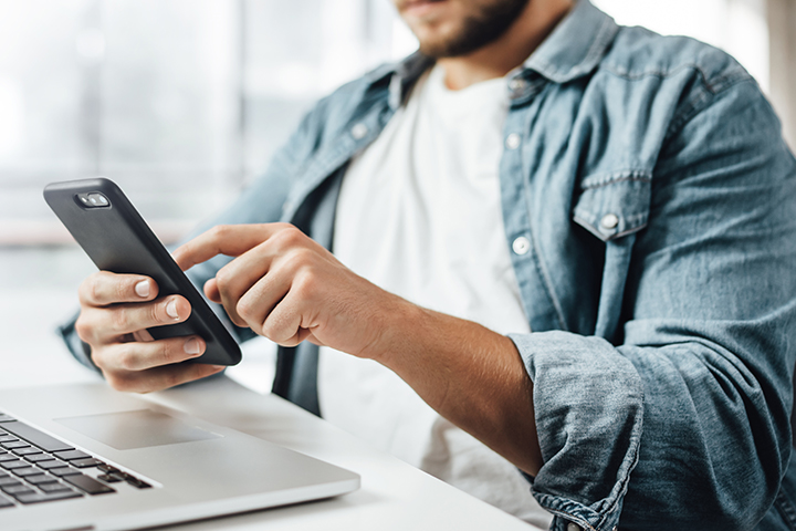 person using smartphone and laptop
