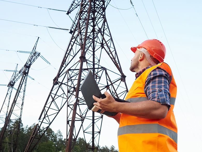 Worker with laptop at power line