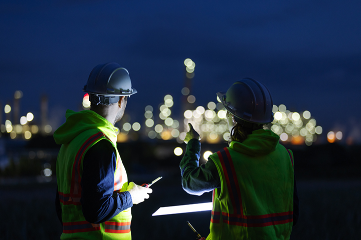 Two workers in hardhats outside at night
