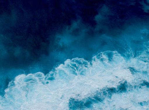 Aerial view of ocean waves with white foam contrasting against deep blue water.