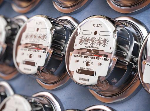 Row of analog electricity meters mounted on a wall, showing dials and measurement indicators.