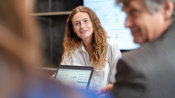 Person at a meeting with a tablet showing charts.