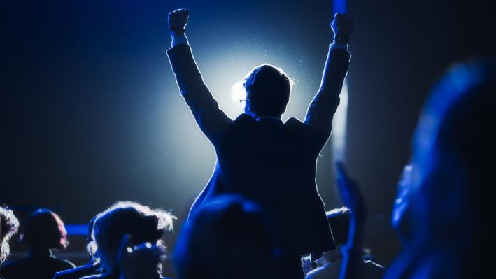 a person standing and cheering in an audience