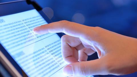 A hand points at text on a screen