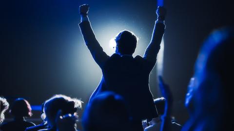 a person standing and cheering in an audience