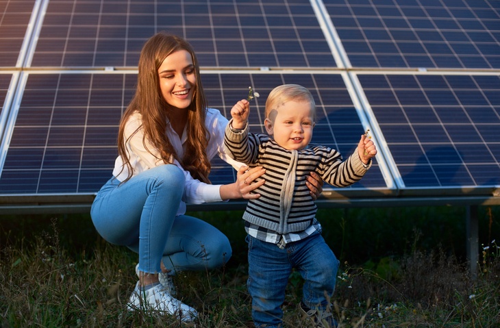 A woman and baby in front of solar panels